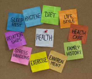 health concept - word cloud or circle of contributing factors (diet lifestyle healthcare family history environment exercise stress relationships sleep rest hygiene) colorful sticky notes on cork bulletin board